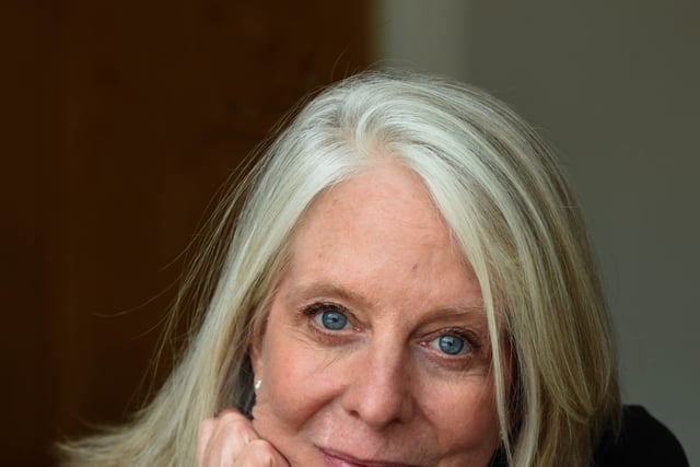 Author Bonnie Garmus, a white woman, rests her head in one hand and looks toward the viewer.