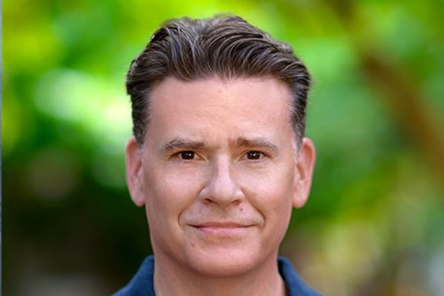 A headshot of Bill Schweigart, a white man with short brown hair slicked back. He is wearing a blue collared shirt and looking at the camera.