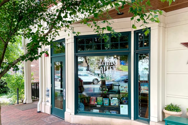 The front of Bards Alley facing Church Street. It shows the front door and large front window, both with a deep green trim. The Bards Alley logo is visible in the window as well as a large shelf of books.